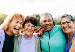 Four active senior women standing together and laughing