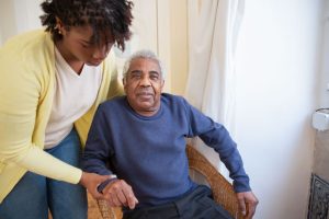 man getting out of a chair with the help of a woman